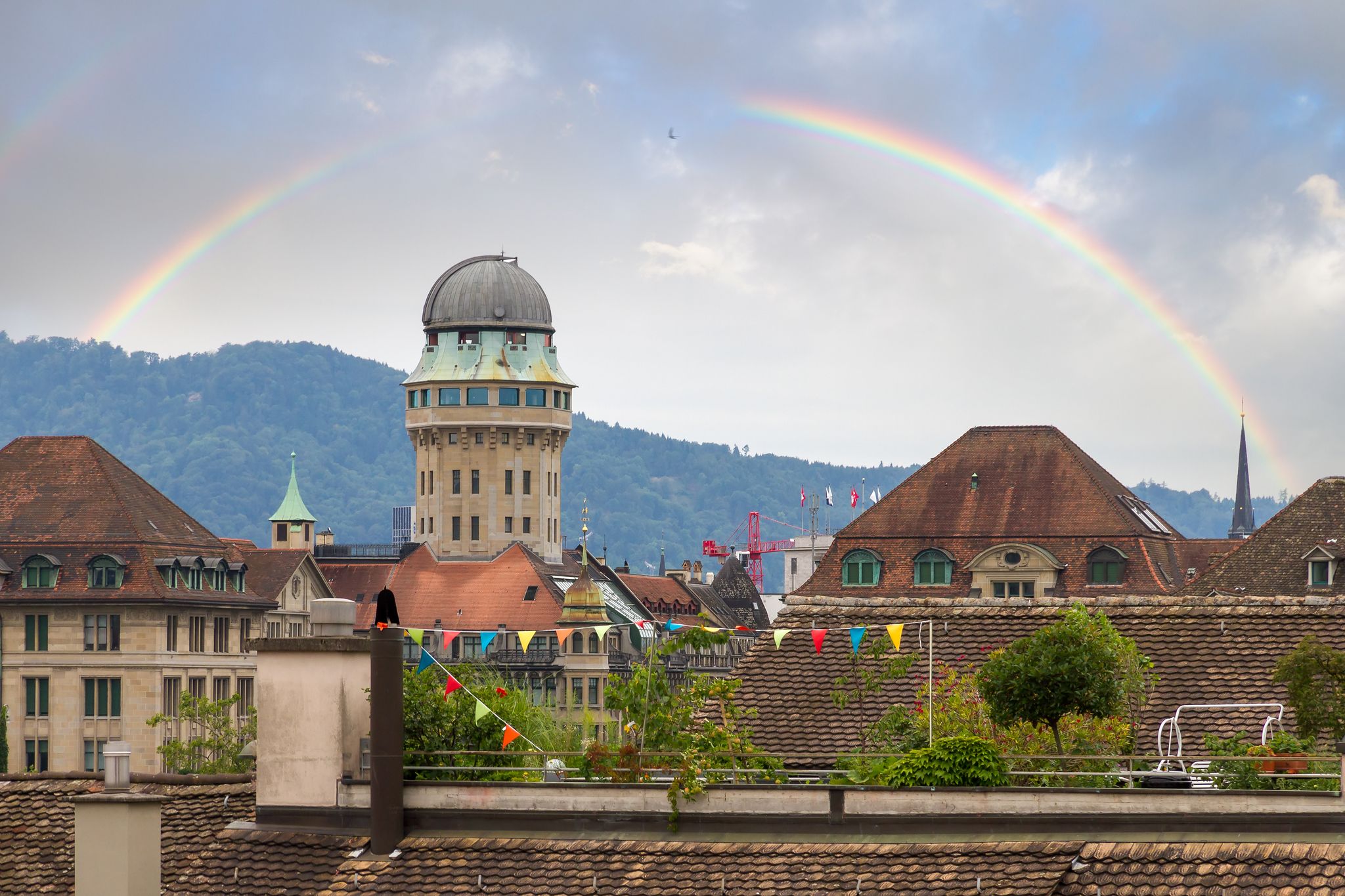 photo of beautiful cityscape looking towards the Urania Sternwarte observatory telescope in Zurich, Switzerland, with a beautiful rainbow in summer.
