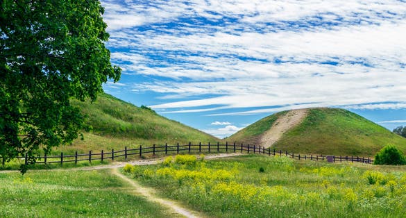 photo of Old Uppsala archaeological area are large barrows located in Gamla Uppsala village, Uppland, Sweden. Beautiful viking graves covered by grass. Gamla Uppsala is area rich in archaeological remains.