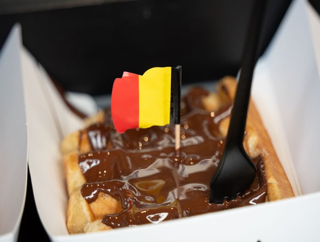Close-up of a Belgian waffle topped with chocolate and a tiny Belgian flag.jpg