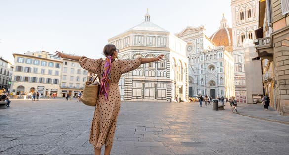 Photo of Woman enjoys beautiful view on famous Duomo cathedral in Florence, standing on empty cathedral square during morning time.