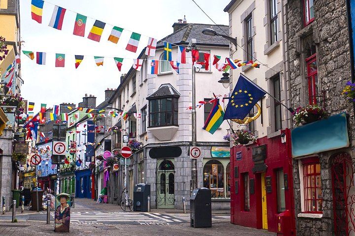 A colorful street in Galway, Ireland, decorated with international flags, lined with shops, pubs, and stone buildings..jpg