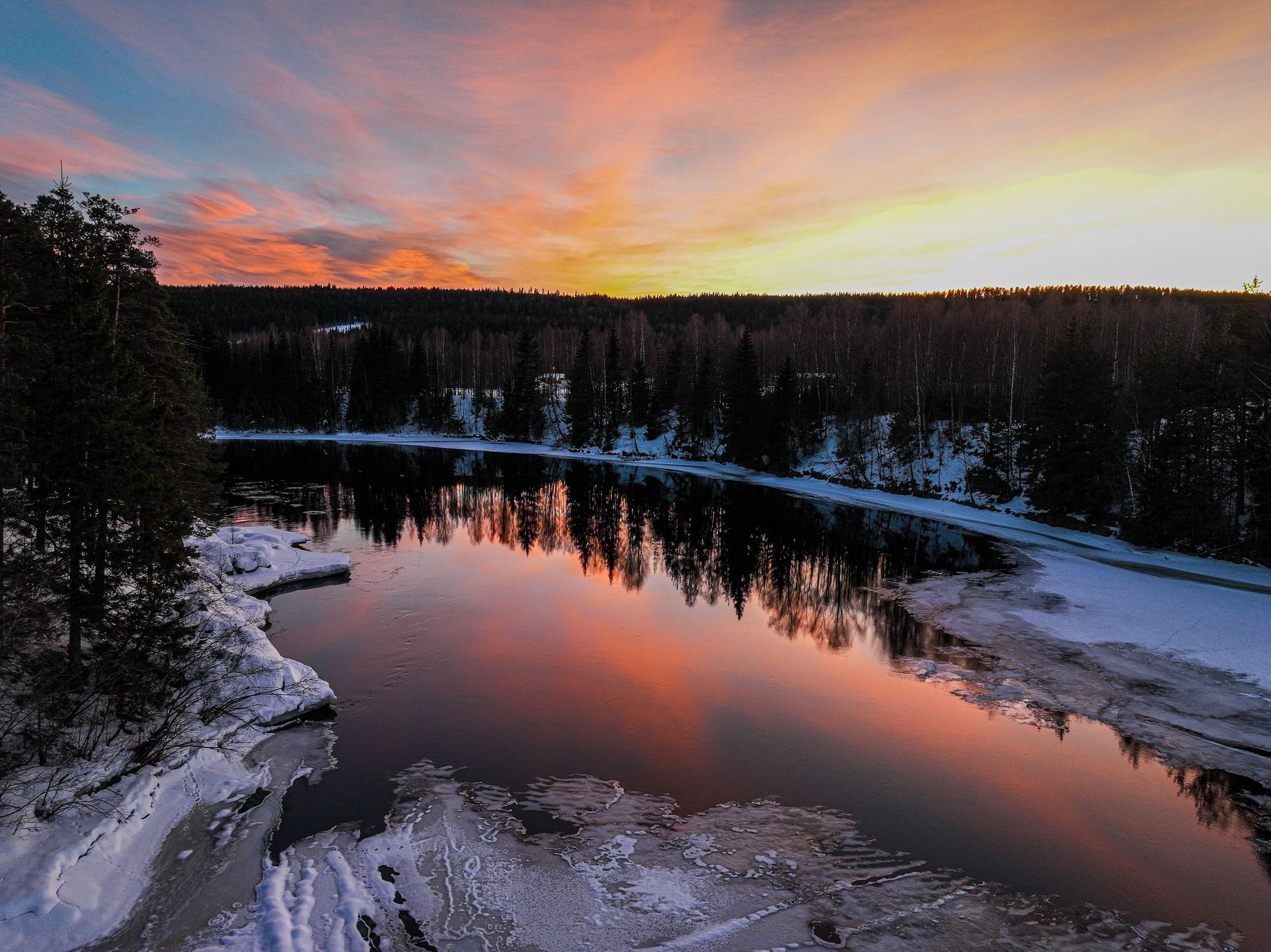 photo of view of A landscape of a pond surrounded by a forest during a breathtaking sunset in Hamar, Norway.