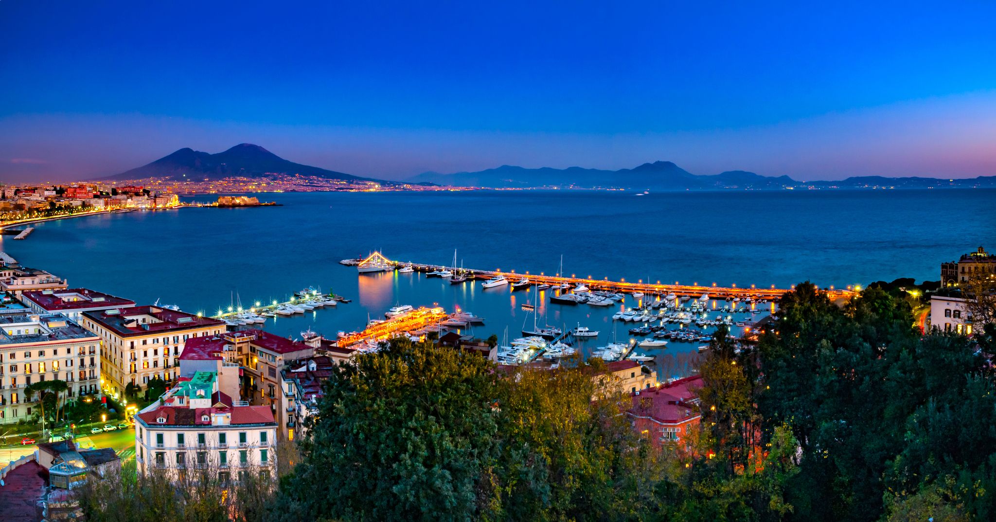 photo of Naples, Italy. Beautiful sunset lights over the Naples' Bay with the marina in foreground and Mount Vesuvius far in the background.,Ottaviano Italy.