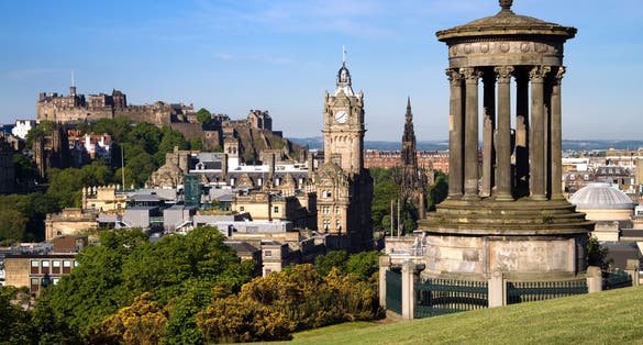 Photo of Edinburgh City and Castle, Scotland, viewed from Calton Hill on a beautiful summer morning with the Dugald Stewart monument in the foreground, Scott monument and Balmoral clock tower in background.