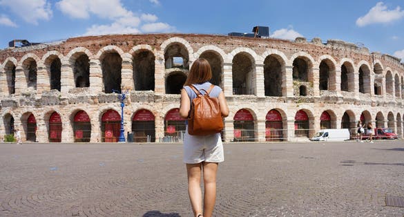 photo of tourism in verona. Back view of tourist woman walks towards verona arena, Italy.