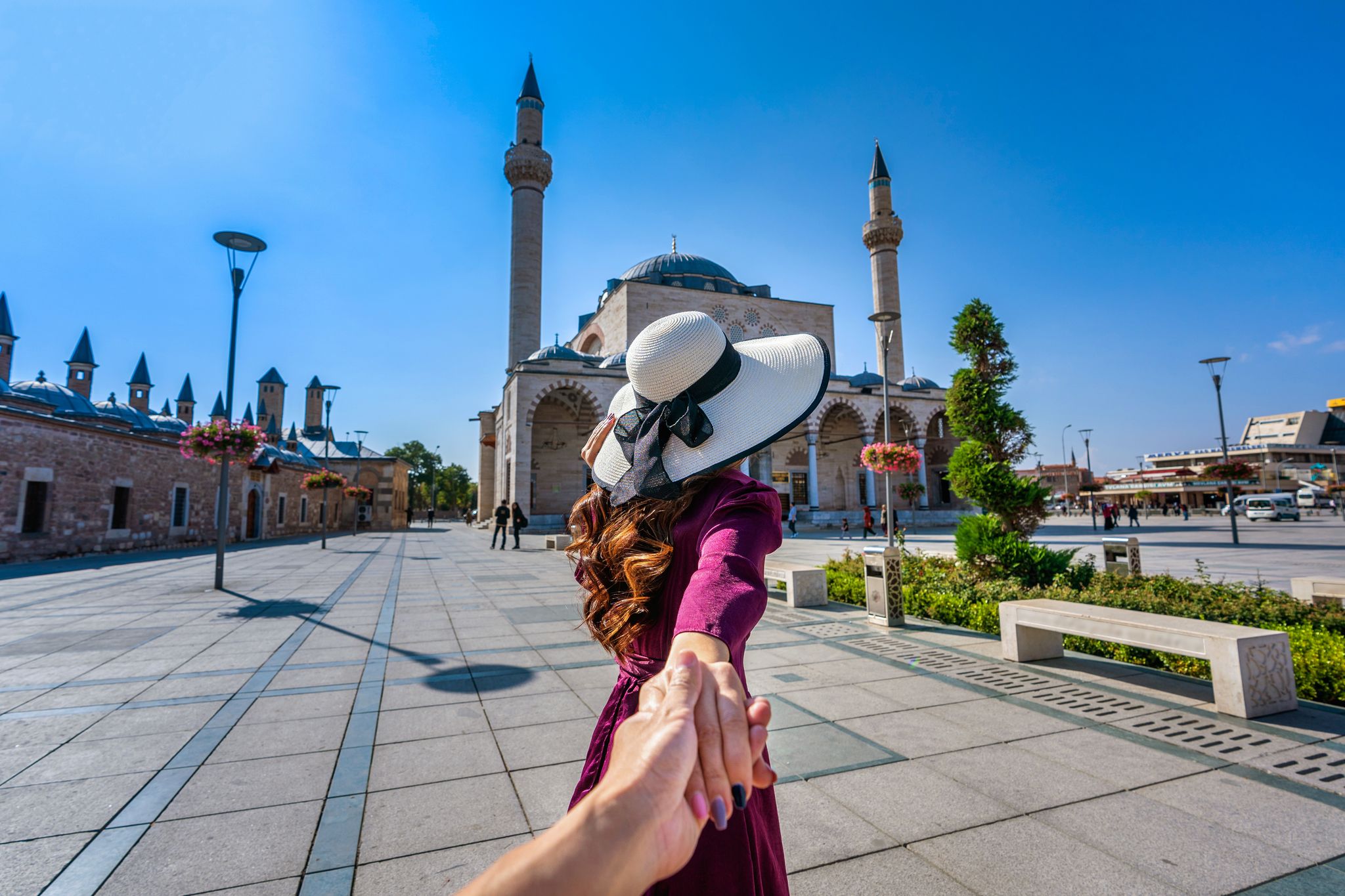 photo of women tourist holding man's hand and leading him to Selimiye Mosque in Konya, Turkey.