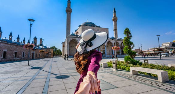 photo of women tourist holding man's hand and leading him to Selimiye Mosque in Konya, Turkey.