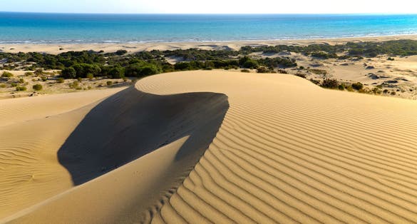 photo of Patara beach is a famous tourist landmark and natural destination in Turkey. Majestic view of orange sand dunes and hills glows in the rays of the warm sunset.