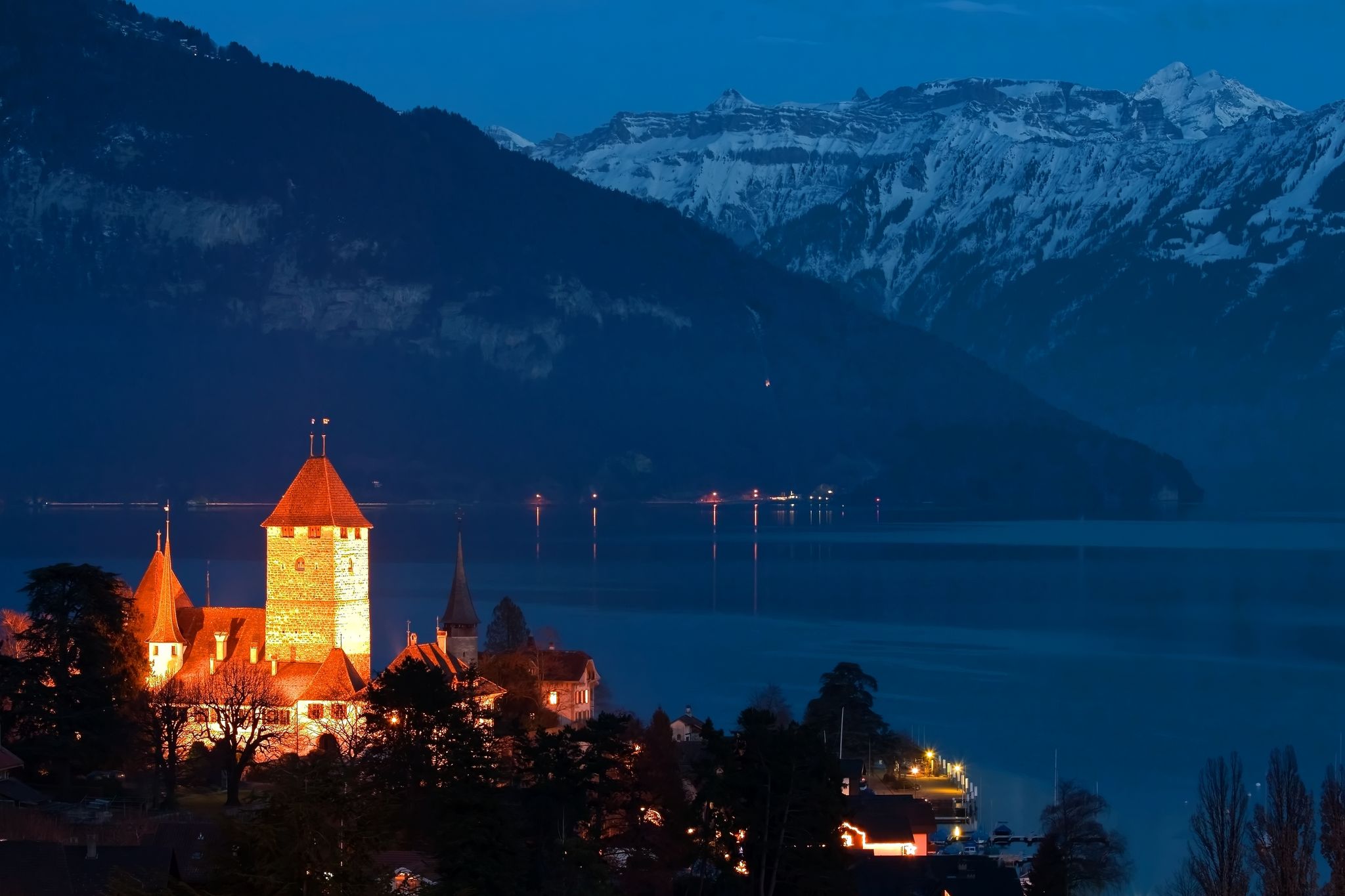 photo of Spize castle and lake Thun background with snow covered Alps mountains night view in Switzerland.