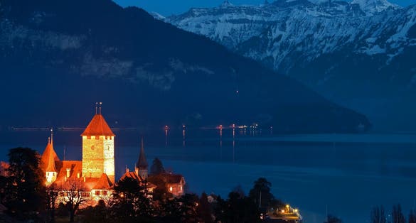 photo of Spize castle and lake Thun background with snow covered Alps mountains night view in Switzerland.