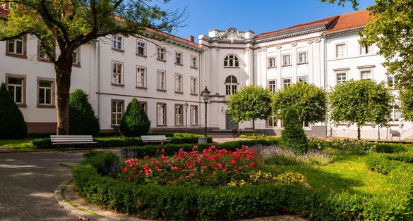 Photo of historic buildings in old town of Göttingen in Lower Saxony, Germany. Sunny day in the public square park called “Wilhelmsplatz“ with the renovated facades of former university refectory or “Mensa“.