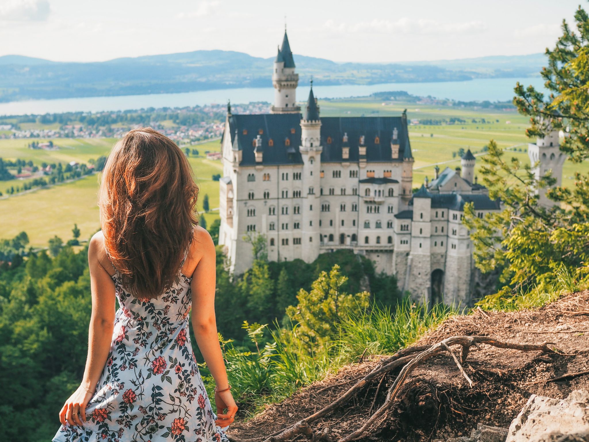 Photo of happy tourist posing on the background of Neuschwanstein castle from a height, Bavaria, Germany.