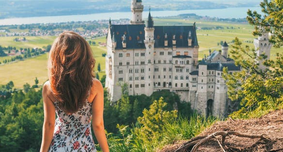 Photo of happy tourist posing on the background of Neuschwanstein castle from a height, Bavaria, Germany.