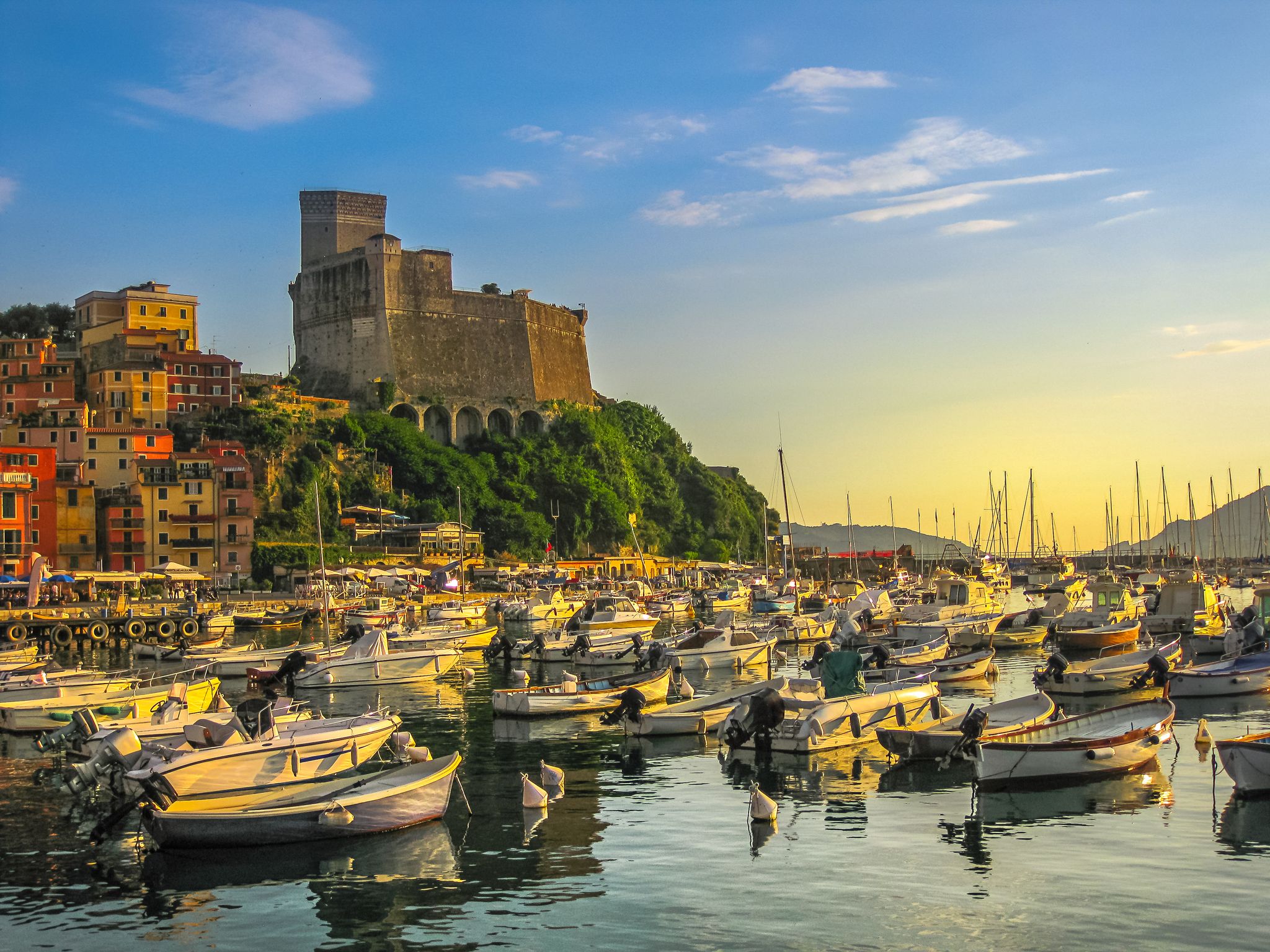 Boats of Lerici docked in Lerici port and famous Italian Gulf of Poets. San Giorgio castle on the background at sunset. La Spezia province, Ligurian Coast of Italy.