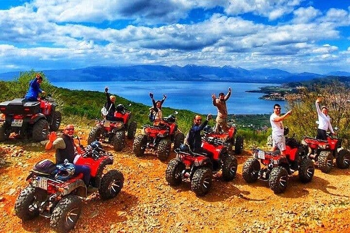 A group of people on red ATVs wave while enjoying a scenic view of Lake Ohrid from a hill in North Macedonia..jpg
