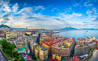 Naples, Italy. View of the Gulf of Naples from the Posillipo hill with Mount Vesuvius far in the background and some pine trees in foreground.