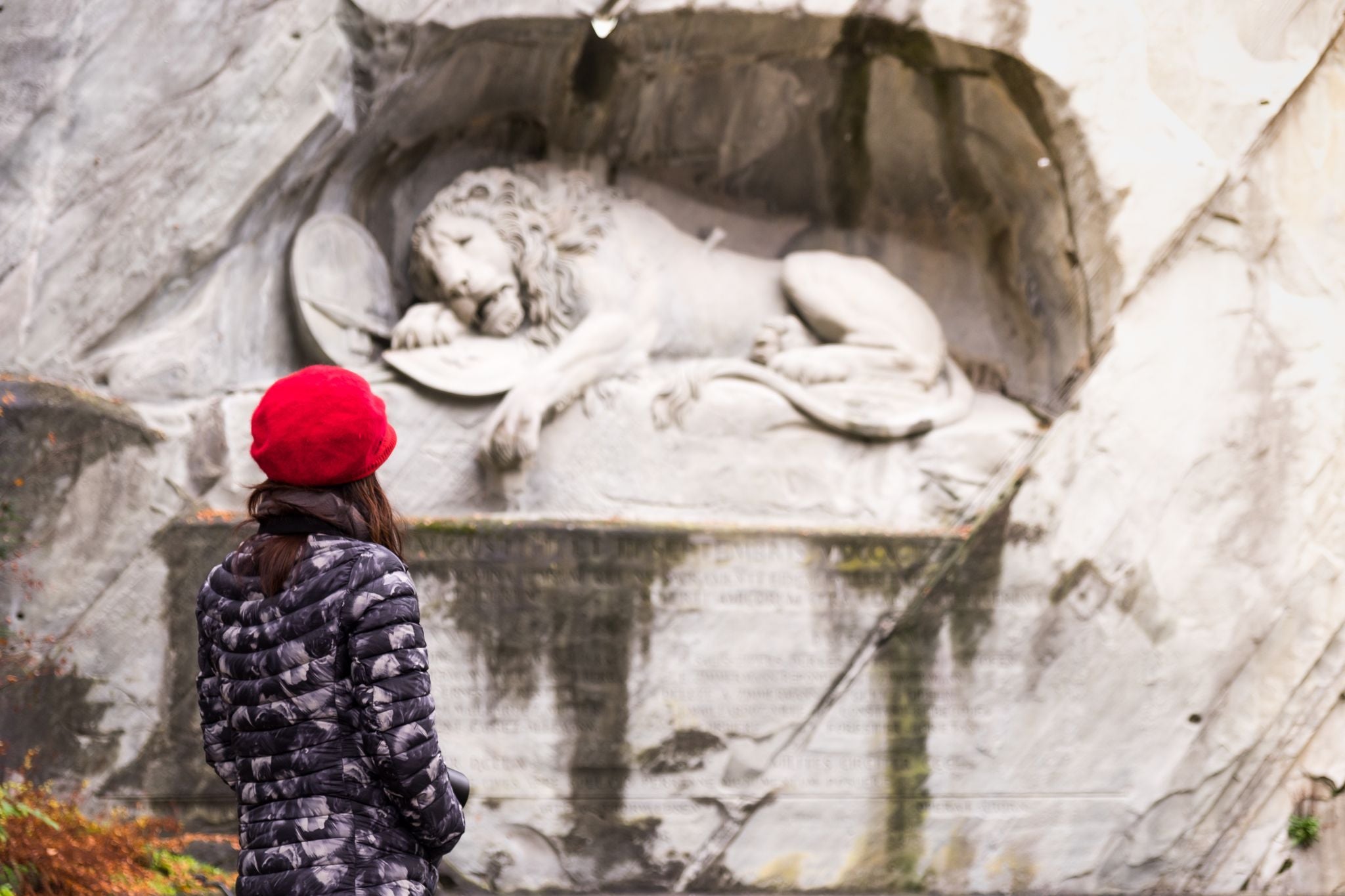 Photo of girl looking at the Lion Monument Lucerne  in Switzerland.