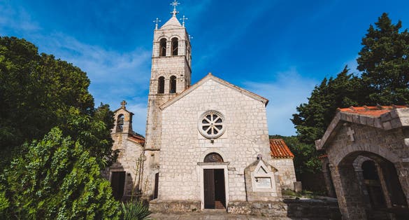 Photo of Rezevici abbey is situated between Budva and Petrovac, Montenegro.Stone belfry and facade of The Serbian Orthodox Rezevici Monastery.