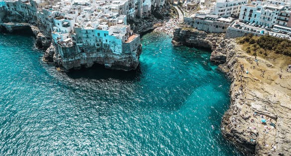 Aerial view of Polignano a Mare, a village built on the edge of the sandstone cliffs above the Adriatic Sea in Apulia, Italy. Drone photography of Lama Monachile bay.