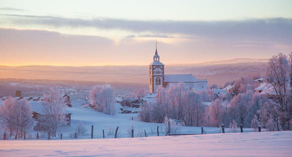 photo of view of Beautiful sunset at the small Norwegian town Roros. Church in the evening sun. Scandinavian winter landscape.