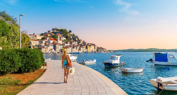 one person walking along the sea with boats, town of Sibenik- travel, tourism in Croatia- Europa