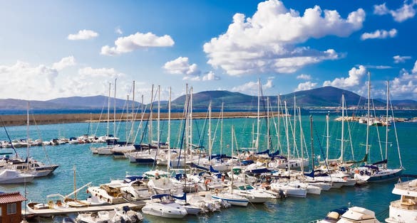 Classic white yachts anchored in the port of Alghero, Sardinia.