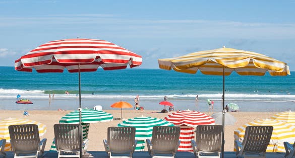 Photo of striped umbrellas on the beach, facing the ocean, Biarritz, France.