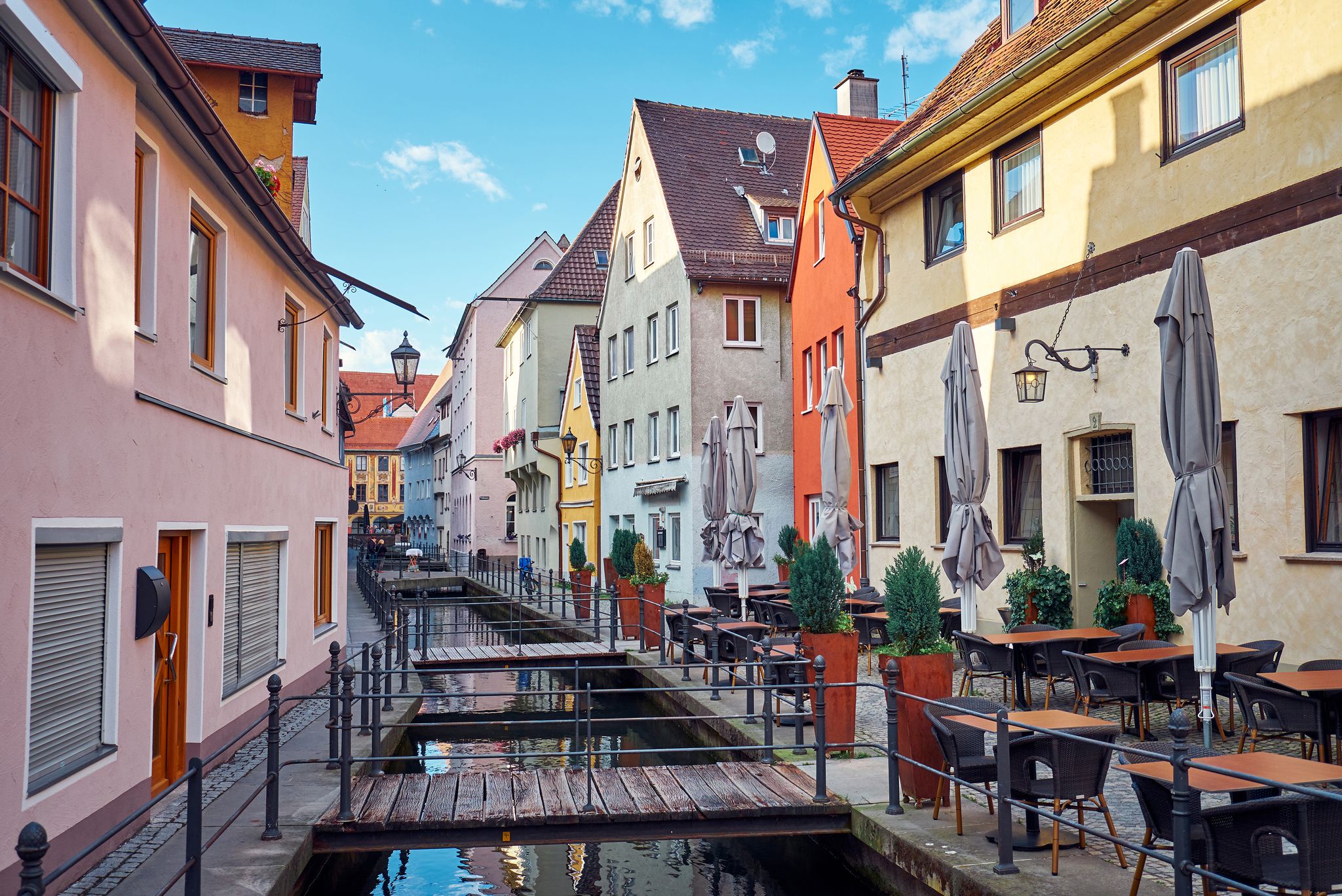 photo of narrow old street with a water canal and restaurant and cafe in Memmingen, Germany.