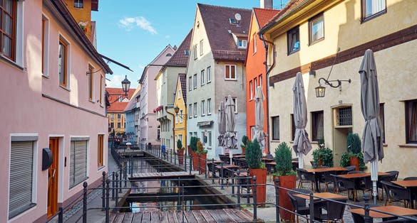 photo of narrow old street with a water canal and restaurant and cafe in Memmingen, Germany.