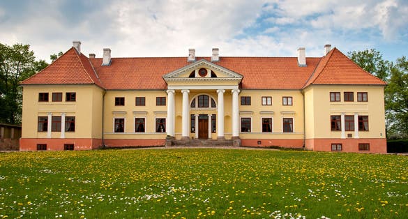 Durbe manor house near Tukums, Latvia with dandelion field in front