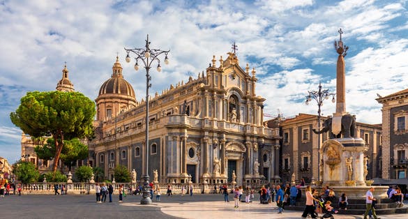 photo of Piazza del Duomo in Catania on a summer day, with Duomo of Saint Agatha and the Elephant Fountain. Sicily, southern Italy. View of Cathedral Sant Agata on Piazza del Duomo in Catania, Sicily, Italy.