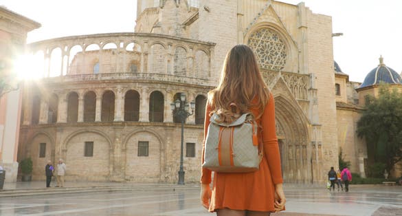 Photo of Tourism in Valencia. Back view of beautiful girl visiting Valencia Cathedral on sunny day. Holidays in Spain.