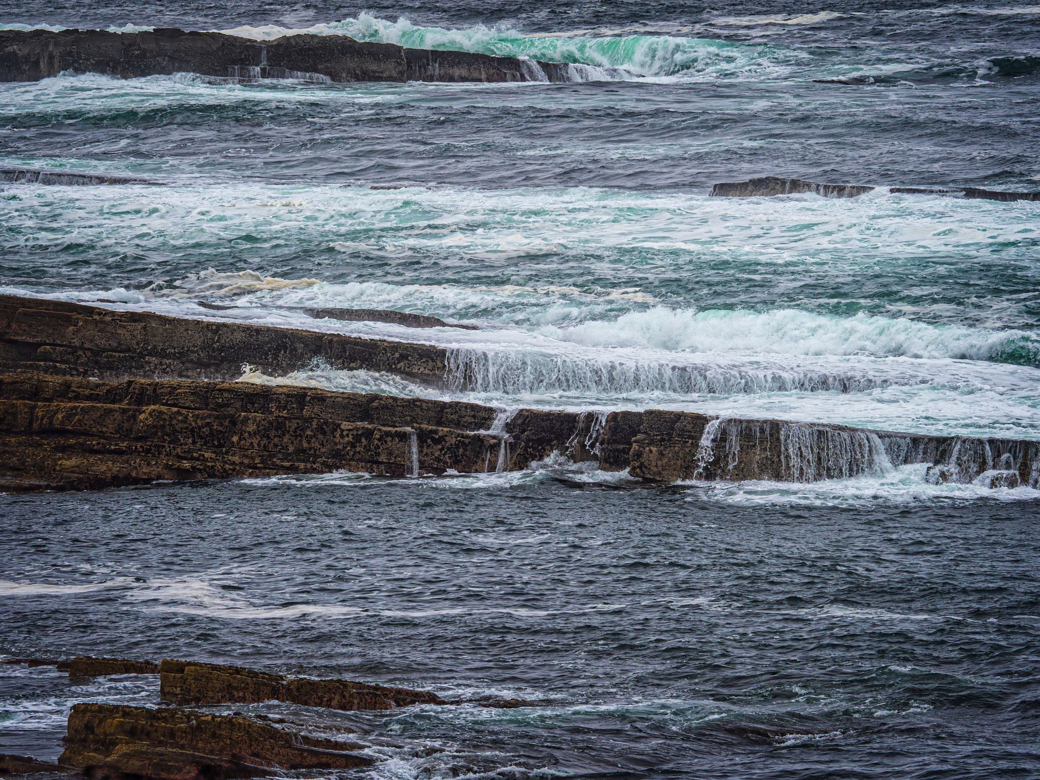 photo of view of A large body of water enclosed by rough grey rocks on the shore at Kilkilloge, County Sligo, Ireland.