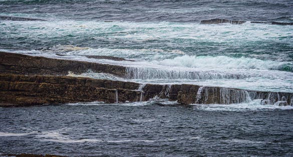 photo of view of A large body of water enclosed by rough grey rocks on the shore at Kilkilloge, County Sligo, Ireland.