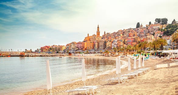 Sunny beach with chairs and umbrellas in Menton, French Riviera, France