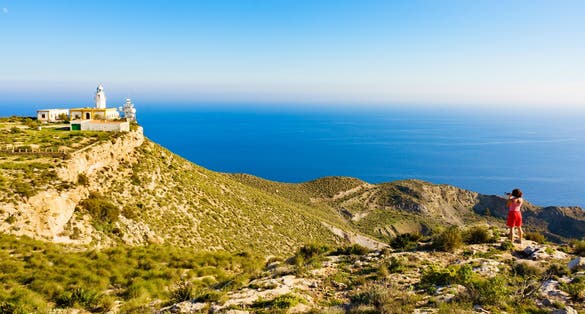 photo of female tourist with camera taking travel photo from Mesa Roldan lighthouse, Cabo de Gata Nijar Natural Park in Almeria, Spain.