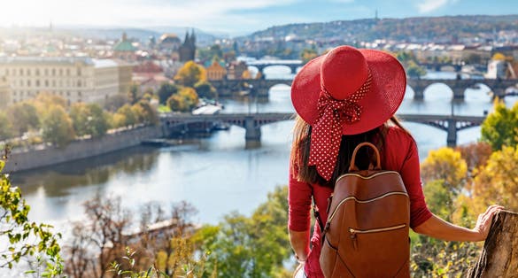Photo of woman enjoys the elevated view over the city of Prague, Czech Republic, on a sunny autumn day.