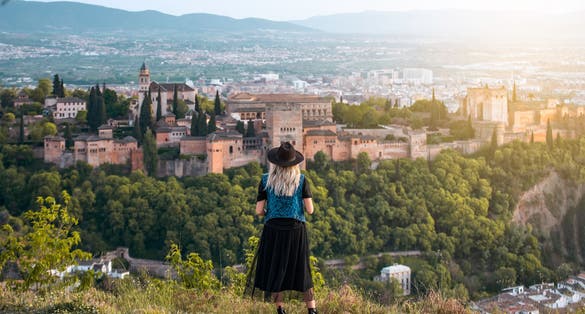 Photo of  young female traveler contemplates the views of the Alhambra palace in the city of Granada, Spain