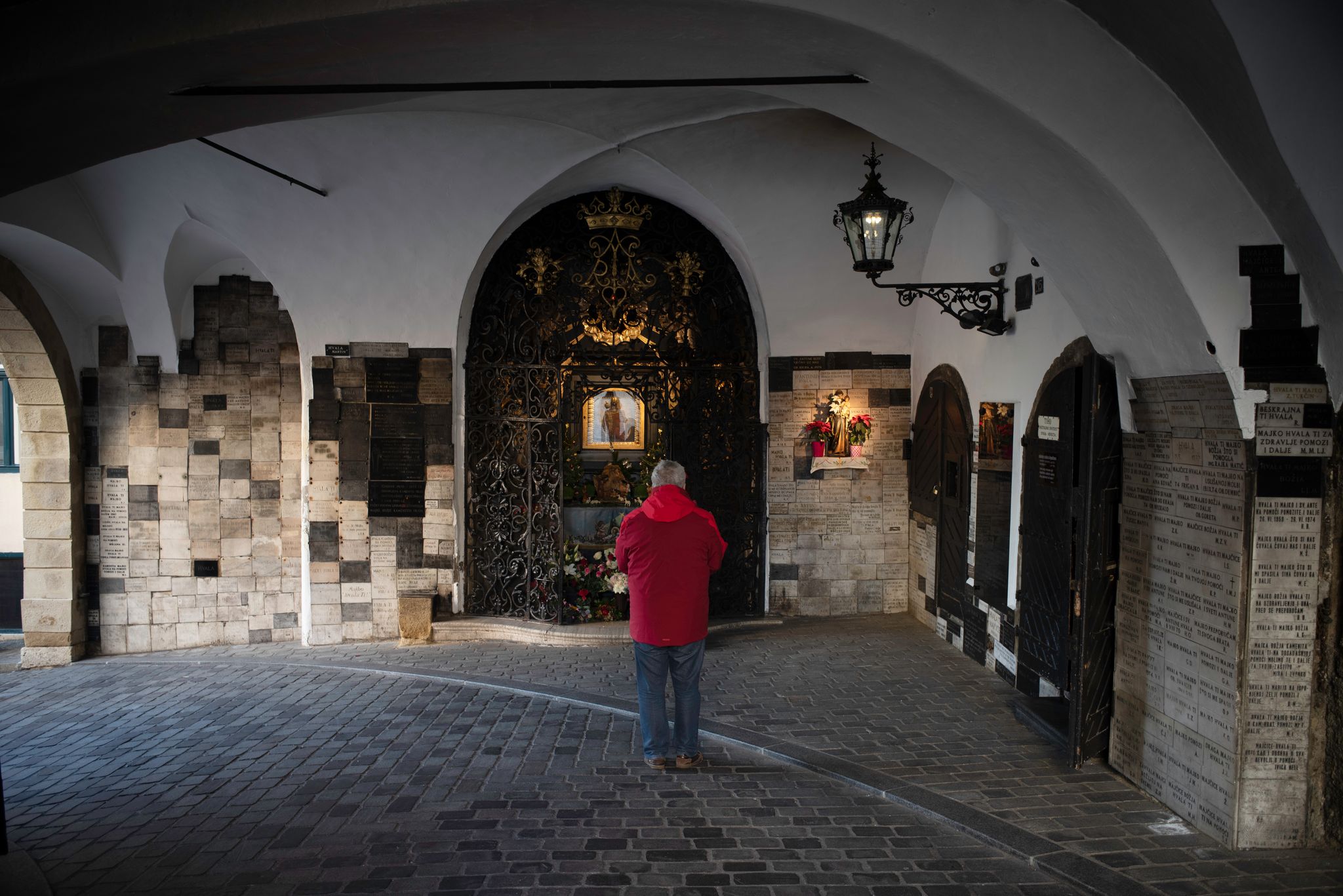 Photo of a man praying at stone gate aka kamenita vrata, Croatia.