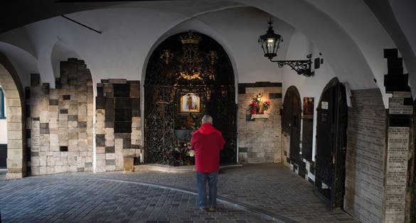 Photo of a man praying at stone gate aka kamenita vrata, Croatia.