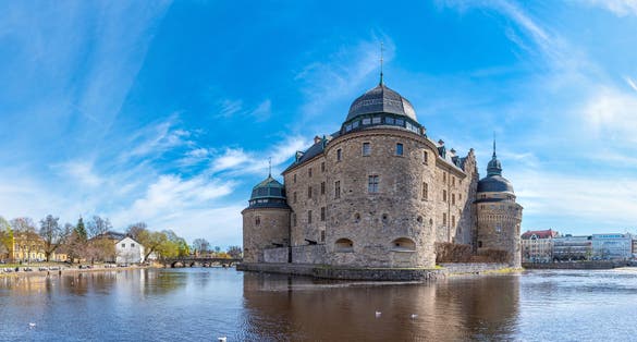 Photo of Orebro castle reflecting in water on sunny summer day in city Orebro, Sweden.