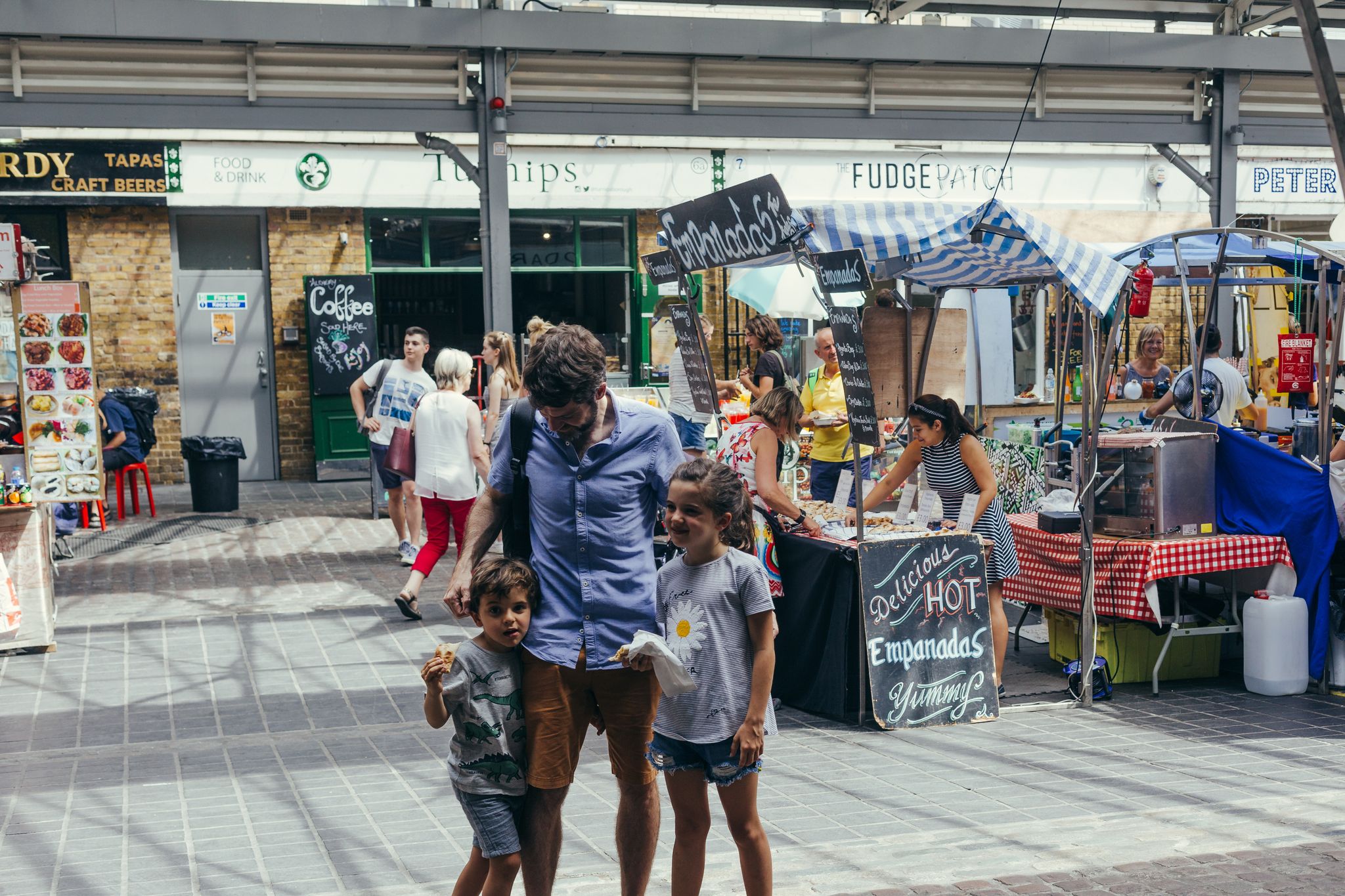 Young family - dad with two kids walking inside the Greenwich Market, one of the oldest markets in London, UK.