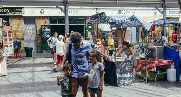 Young family - dad with two kids walking inside the Greenwich Market, one of the oldest markets in London, UK.