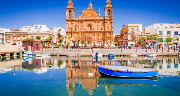 Photo of Msida Marina boat and church reflection into water, Malta.