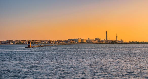 Breakwater of Aveiro estuary with buildings and Barra lighthouse in the horizon at golden hour, Gafanha da Nazaré PORTUGAL
