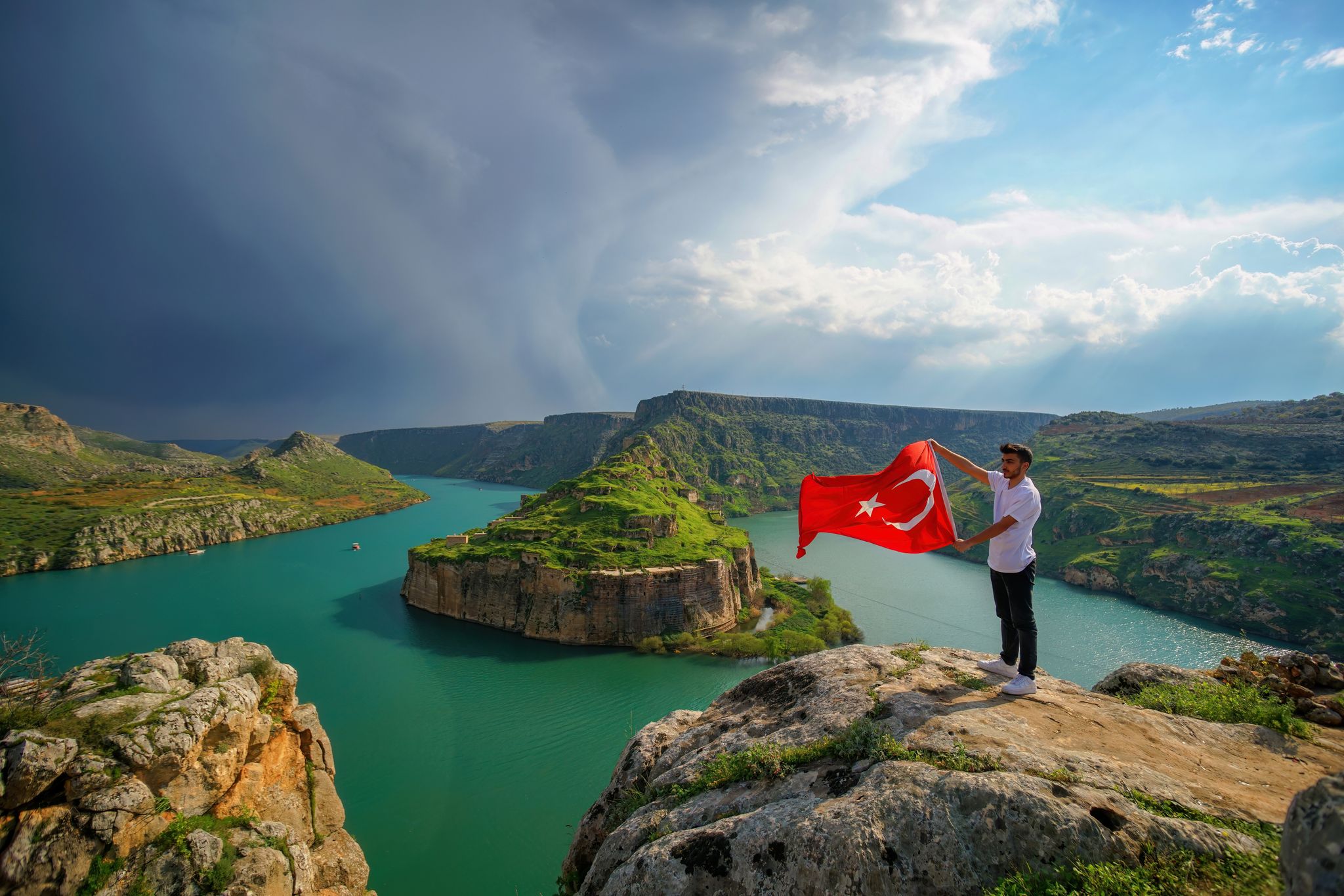 photo of Rumkale view and a young man with Turkish flag in front of the landscape in Kasaba, Turkey.