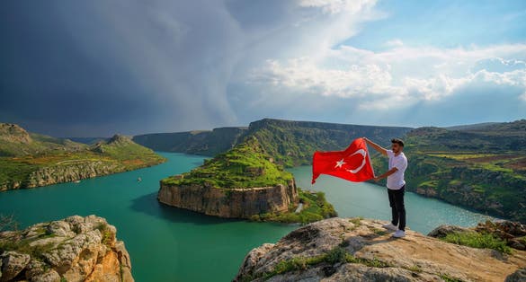 photo of Rumkale view and a young man with Turkish flag in front of the landscape in Kasaba, Turkey.