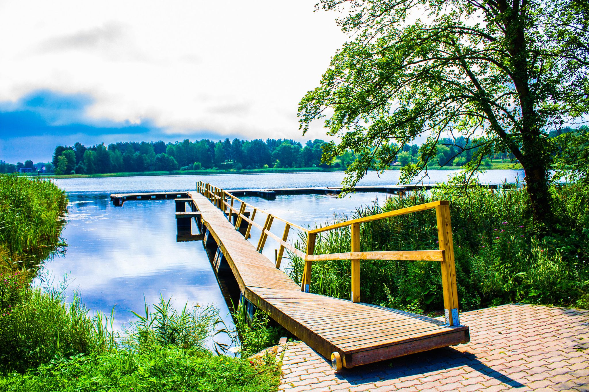 Beautiful lake park on a bright sunny summer day near Trakai Castle in Lithuania, Europe. Lake Galvė is a lake in Trakai Lithuania. Lake and Forest Panorama, blue sky, yellow boat dock.