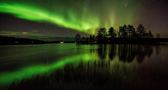 Photo of northern lights and it's reflection in the lake in Kuusamo, Finland.