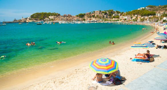 Colorful umbrellas on Puerto de Soller, Port of Mallorca island in balearic islands, Spain. Beautiful picture of people resting on the beach on bright summer day.